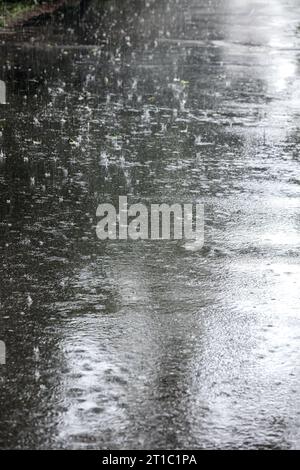 trottoir inondé pendant de fortes pluies avec éclaboussures de gouttes de pluie sur la surface de l'eau Banque D'Images