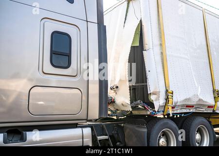 Tracteur de semi-camion de grande plate-forme industrielle beige avec semi-remorque sèche de van cassé attaché par élingue debout sur la rue de la ville en attente pour possible Banque D'Images