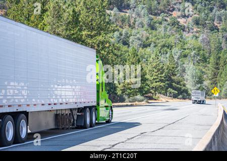 Tracteur de semi-camion big RIG de transporteur industriel vert avec cabine allongée pour le repos du conducteur de camion transportant des marchandises dans une semi-remorque réfrigérée fonctionnant sur le Banque D'Images