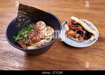 Soupe traditionnelle japonaise ramen, nouilles, chiken tranché, œufs et Bao avec poulet, sauce, oignon et graines de sésame Banque D'Images