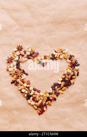 Assortiment de noix, raisins secs et canneberges en forme de cœur esthétique. Nourriture saine et collations. Noix, amandes, noisettes et noix de cajou Banque D'Images