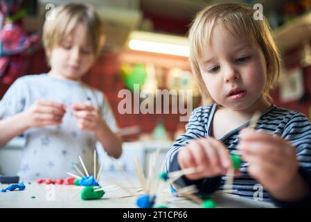 Deux frères fabriquent des figures tridimensionnelles de plasticine et de bâtons. Banque D'Images