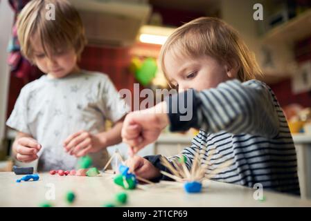 Deux frères fabriquent des figures tridimensionnelles de plasticine et de bâtons. Banque D'Images