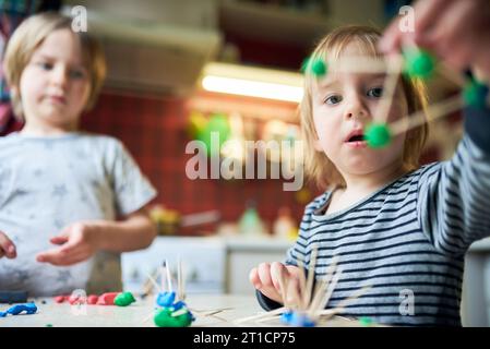 Deux frères fabriquent des figures tridimensionnelles de plasticine et de bâtons. Banque D'Images