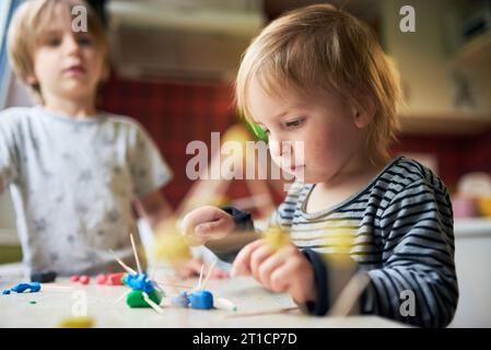 Deux frères fabriquent des figures tridimensionnelles de plasticine et de bâtons. Banque D'Images