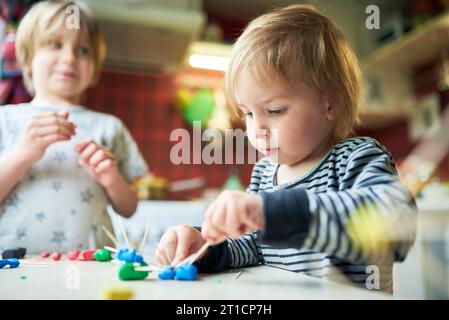 Deux frères fabriquent des figures tridimensionnelles de plasticine et de bâtons. Banque D'Images