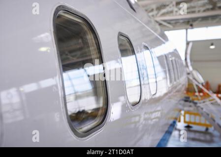 Vue rapprochée sur les illuminateurs d'avions de passagers debout sur la place de stationnement au hangar de l'aéroport. personne Banque D'Images