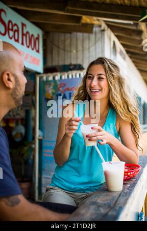 Une belle femme profite d'une pina colada dans un bar de plongée à Porto Rico. Banque D'Images