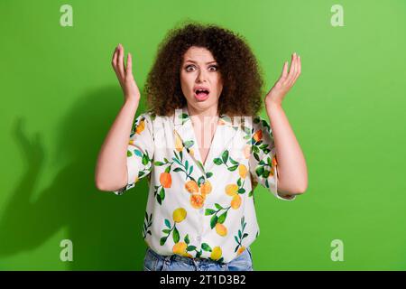 Portrait de fille insatisfaite impressionnée lever les bras la bouche ouverte ne comprennent pas isolé sur fond de couleur verte Banque D'Images