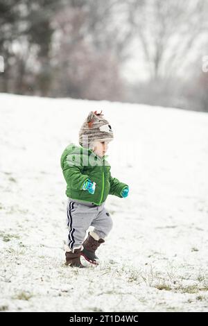 Tout-petit marchant dans la neige portant des vêtements d'hiver Banque D'Images