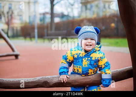 Petit garçon dans une veste bleue sur la cour de récréation dans le parc. Banque D'Images