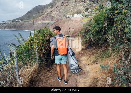 Un homme avec une planche de surf caché sous son bras étudiant les vagues Banque D'Images