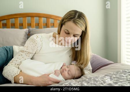 Mère et nouveau-né couchés sur le lit ; mère regardant le bébé souriant Banque D'Images