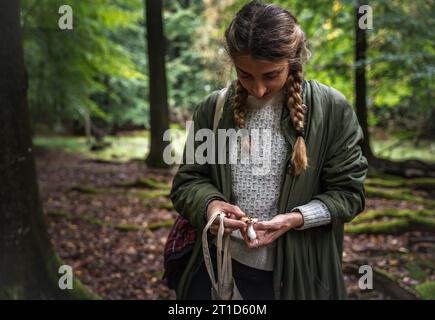 Femme avec de longues tresses identifiant les champignons en Scandinavie Banque D'Images