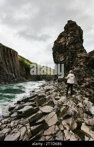 Femme grimpe et randonnées sur les rochers dans la vallée de falaise avec rivière Banque D'Images