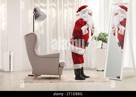 Plan de profil en longueur du père noël se préparant devant un miroir à la maison Banque D'Images