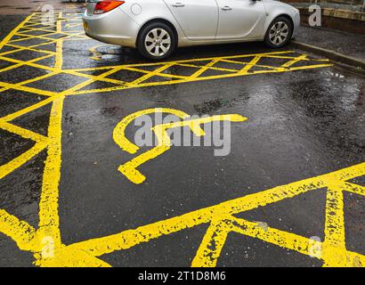 Marquage routier jaune sur la route pour identifier les multiples places de stationnement diablées au Royaume-Uni. Panneau de stationnement pour personnes handicapées. Parking handicapés, citi handicapés Banque D'Images