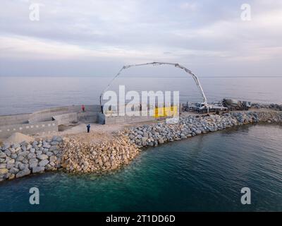 L'équipement de construction lourd construit un brise-lames. Couler du béton sur une jetée en construction dans la mer. vue aérienne. Banque D'Images