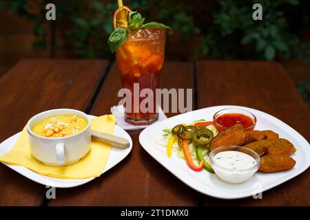 Bol de soupe de maïs sucré avec pop-corn et nuggets de poulet avec sauce salsa, sauce à l'ail et légumes Banque D'Images