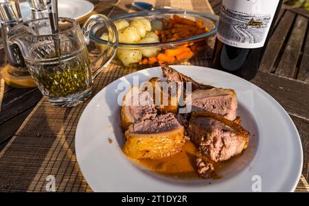 Assiette à dîner avec agneau à la sauce à la menthe, pommes de terre et carottes, bouteille de vin Banque D'Images