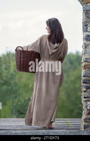 Femme médiévale en vue arrière avec panier et cheveux longs Banque D'Images