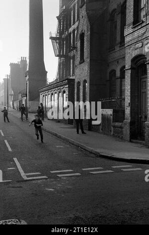 Groupe de garçons jouant au football devant l'usine Cooper and Roe sur Heskey Street, St ann's, Nottingham pendant le déminage et la démolition des bidonvilles 1969-72 Banque D'Images