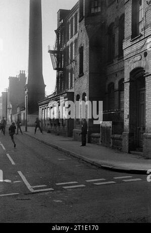 Groupe de garçons jouant au football devant l'usine Cooper and Roe sur Heskey Street, St ann's, Nottingham pendant le déminage et la démolition des bidonvilles 1969-72 Banque D'Images