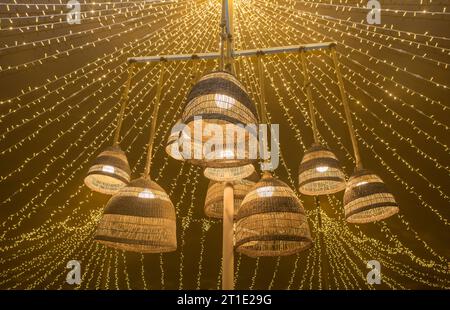 Lampes en fibre naturelle suspendues au plafond d'une tente avec un fond de guirlandes LED. Ambiance chaleureuse Banque D'Images