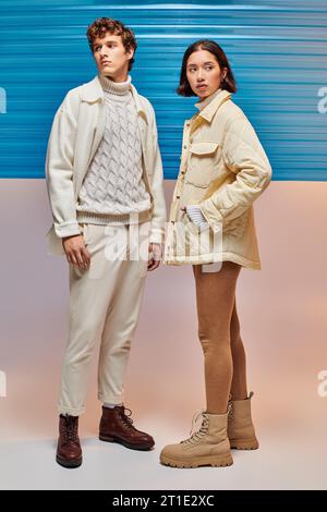 modèles multiethniques en vestes chaudes et bottes en cuir près de la feuille de plastique bleue, mode hiver Banque D'Images