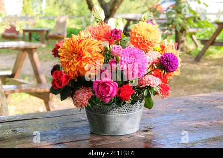Roses, asters, dahilia dans le jardin de pommiers sur une table en bois. Design floristique. Fleurs en journée ensoleillée. La vie à la campagne. Banque D'Images