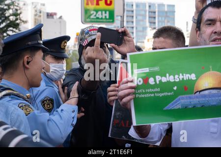 Tokyo, Japon. 13 octobre 2023. Un manifestant portant un chapeau Trump 2024 flippe la presse alors qu’il se disputait avec des policiers de Tokyo lors d’un rassemblement pro-palestinien. Des membres de la communauté islamique au Japon et des partisans japonais protestent devant l’ambassade israélienne en solidarité avec la Palestine et contre Israël au début de la guerre à Gaza Strip après que le groupe militant du Hamas ait lancé une attaque d'incursion terrestre en Israël. Israël et l'armée israélienne ont commencé à amasser des troupes à la frontière et ont mis un siège à la bande de Gaza en bloquant la nourriture, l'électricité et l'eau. (Image de crédit : © Taidgh Barron/ZUMA Pre Banque D'Images