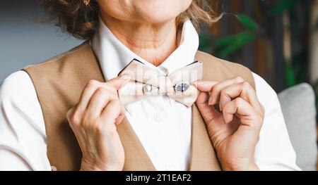 Confiante élégante femme d'affaires âgée d'âge moyen mûr en costume, chemise blanche, épingle de noeud papillon avec des pierres précieuses, bijoux, diamants, strass. GE Banque D'Images