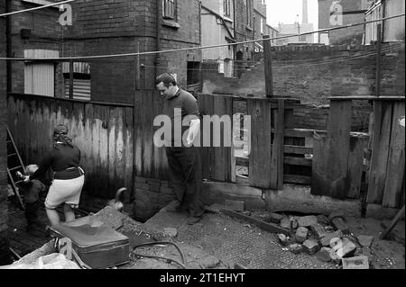 Famille avec leur chien dans l'arrière-cour de leur maison mitoyenne victorienne pendant le nettoyage des bidonvilles et la démolition de St ann's, Nottingham. 1969-1972. Banque D'Images