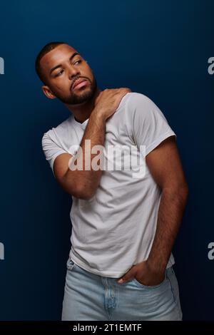 jeune afro-américain en chemise blanche et jeans gestionnant et regardant loin, concept de mode Banque D'Images