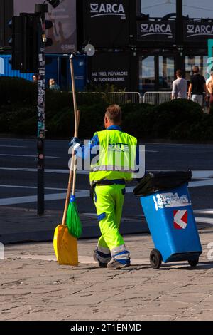 Trieste, Italie – 30 septembre 2023 : un homme vêtu d'uniforme jaune ramasse des ordures, nettoie les rues. Dépoussiéreur, dépoussiéreur, poubelle, cendres Banque D'Images