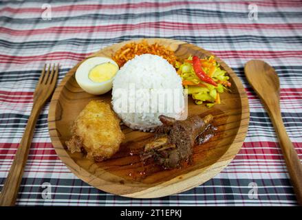 Riz au poulet épicé rouge avec concombre mariné et carottes, œuf dur, beignets de pommes de terre et pommes de terre frites épicées sucrées. Banque D'Images