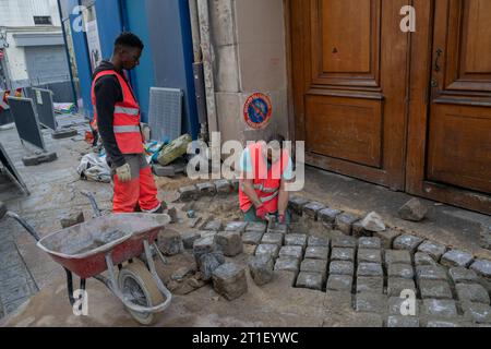 Paris France vie quotidienne authentique, deux hommes refaisant un trottoir Banque D'Images