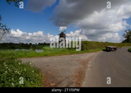 Un paysage rural dans l'Essex avec un moulin à vent près d'un étang, par une ruelle avec un vieux chariot en bois Banque D'Images