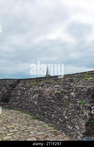 Angers, France, 2023. Le clocher de l'église Saint-Laud vu des remparts de pierre et d'ardoise du Château d'Angers (vertical) Banque D'Images