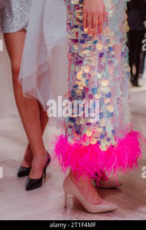 Les mannequins sur les coulisses habillés dans un long boudoir haute couture habillent tenues et talons hauts. Préparation avant le défilé de mode Banque D'Images