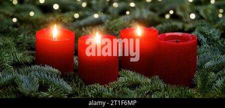 Bougies rouges de l'Avent, trois brûlantes, avec des branches de sapin et des lumières de bokeh. L'image fait partie d'un ensemble. Banque D'Images