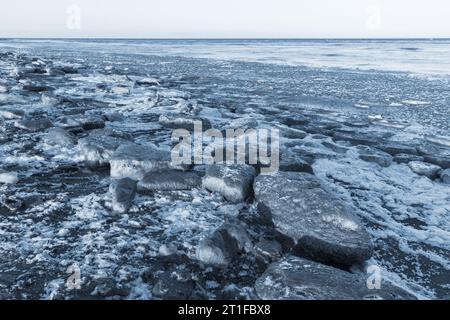 Les floes de glace reposent sur la côte de la mer Baltique sur un fond naturel d'hiver de jour. Fond photo teinté de bleu Banque D'Images