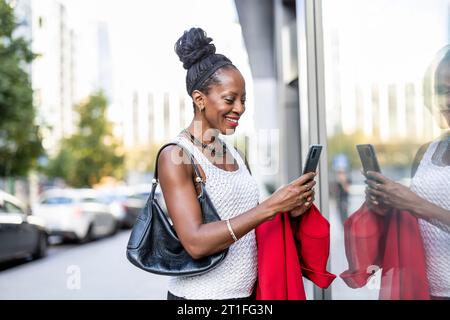 Portrait de femme souriante avec téléphone portable dans la ville Banque D'Images