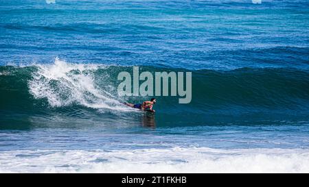 Homme allongé sur son surf dans une vague à Anglet, France Banque D'Images