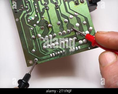 Réparateur effectuant des mesures sur la carte de circuit électronique. Banque D'Images