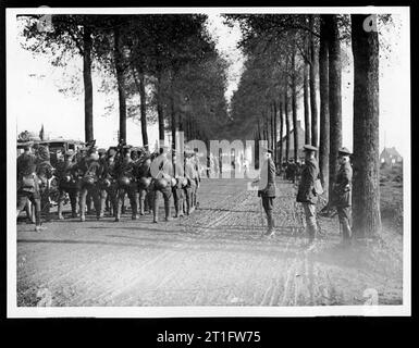 Photographies des visites royales sur le front occidental. Les visites royales étaient considérées comme un moyen important de remonter le moral. Les troupes irlandaises marchent le long d'une route poussiéreuse bordée d'arbres. Certaines des troupes jouent de la cornemuse. Les spectateurs regardent du côté de la route. Au loin se trouvent un certain nombre de véhicules et un homme sur un cheval gris. Le duc de Connaught était le troisième fils de la reine Victoria. Le général Plumer a été célébré pour avoir mené avec succès la bataille de Messines Ridge en 1917. [L'original se lit comme suit : 'PHOTO OFFICIELLE PRISE SUR LE FRONT occidental - les troupes irlandaises défilent devant le duc de Connaught et le général Sir Herbert Banque D'Images