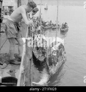 La réoccupation britannique de Hong Kong, 1945 sampans chinois accostent Landing Ship Tank LST 304 alors qu'elle entre dans le port de Hong Kong. LST 304 a navigué dans le cadre du premier convoi à Hong Kong après la reddition du Japon. Banque D'Images