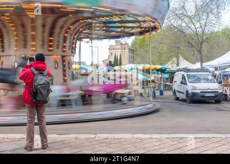 Un touriste prend une photo d'un manège en action au marché en plein air de Saurday à Arles, en Provence, dans le sud de la France. Banque D'Images