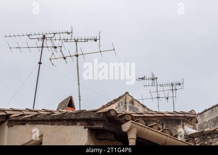 Antennes TV sur les toits en terre cuite en pente dans la ville antique d'Arles en Provence, dans le sud de la France. Une pie est assise sur une antenne. Banque D'Images