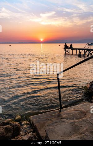 Vue sur le lac au coucher du soleil de Walkway à Cisano, Bardolino, Lac de Garde, Italie Banque D'Images